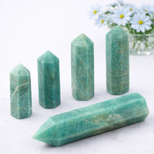 Amazonite crystal tower point on white background with soft shadow and blurred light blue daisy vase behind